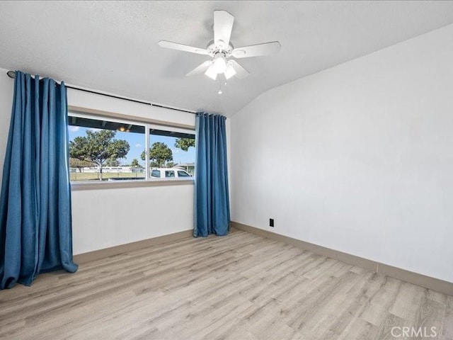 unfurnished room with vaulted ceiling, ceiling fan, wood finished floors, and baseboards