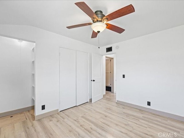 unfurnished bedroom featuring baseboards, visible vents, ceiling fan, light wood-type flooring, and multiple closets