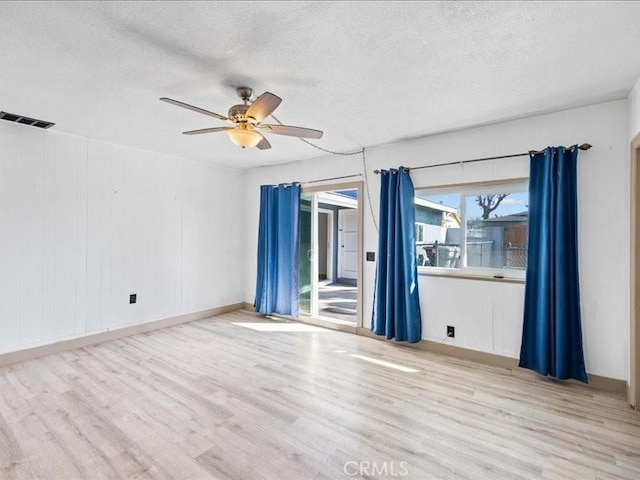 spare room featuring a ceiling fan, visible vents, a textured ceiling, and wood finished floors