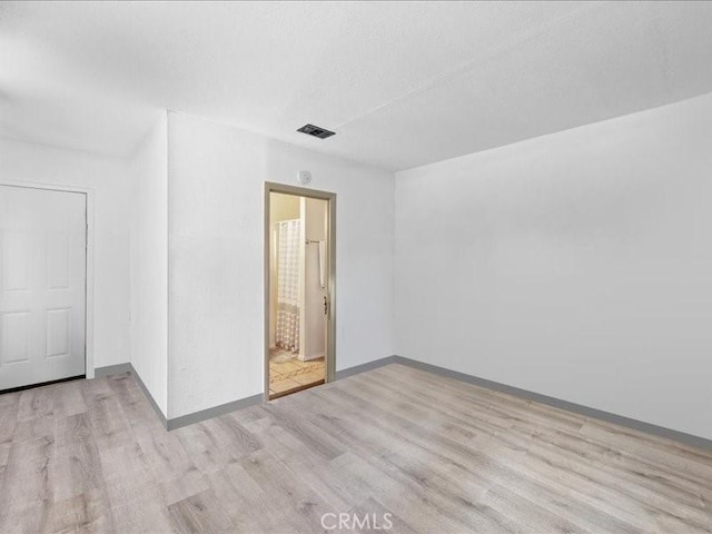 unfurnished room with visible vents, a textured ceiling, baseboards, and wood finished floors