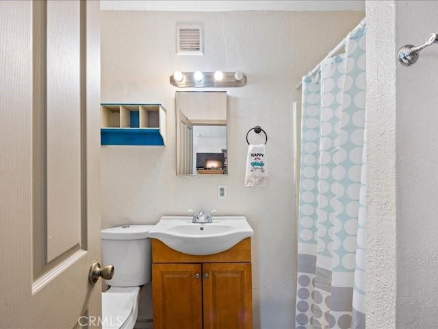 full bath featuring toilet, curtained shower, vanity, and visible vents