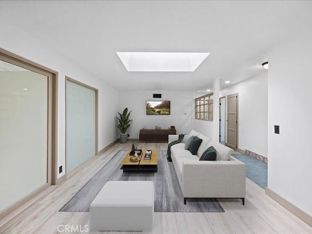 living room with a skylight, wood finished floors, visible vents, and baseboards