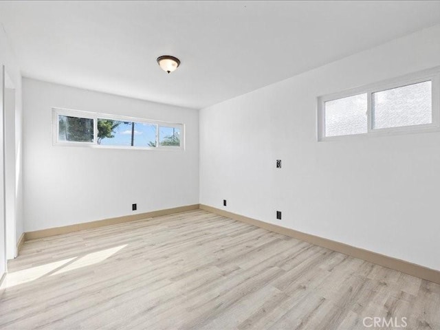 unfurnished room with light wood-style flooring and baseboards