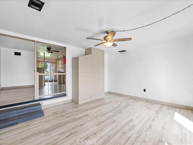 interior space with baseboards, wood finished floors, visible vents, and a ceiling fan