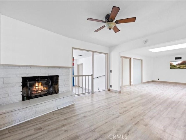 unfurnished living room with visible vents, a fireplace, baseboards, and wood finished floors