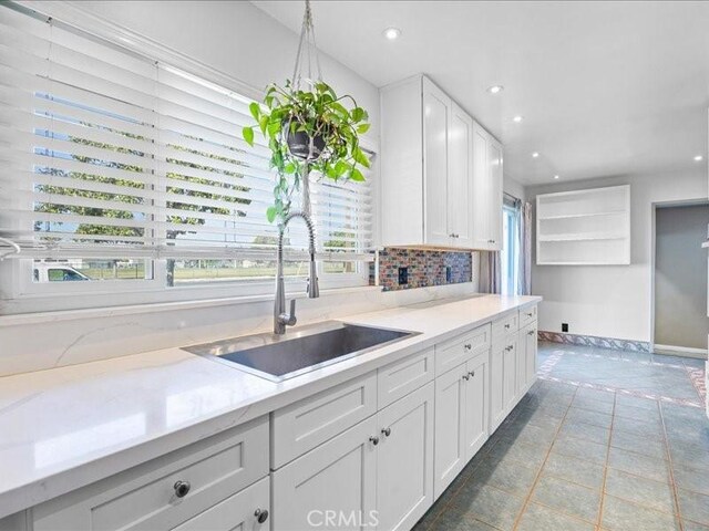 kitchen with decorative backsplash, tile patterned floors, white cabinetry, a sink, and recessed lighting