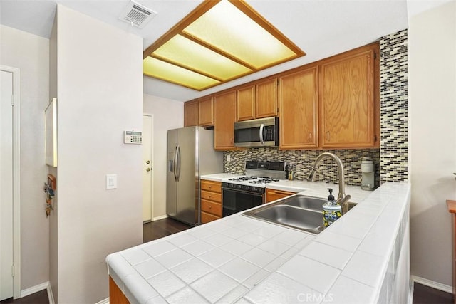 kitchen featuring appliances with stainless steel finishes, tile counters, visible vents, and a sink