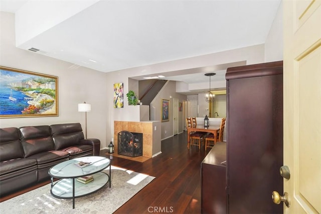 living area featuring baseboards, visible vents, dark wood-type flooring, and a tile fireplace