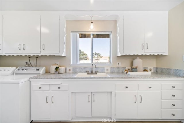 interior space featuring cabinet space, a sink, and independent washer and dryer