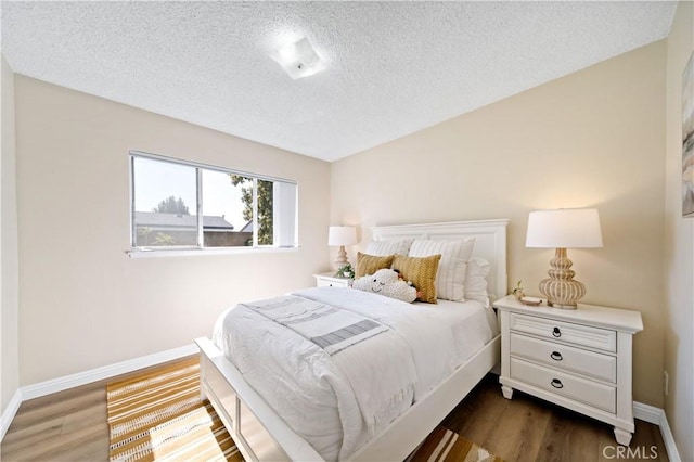 bedroom with baseboards, dark wood finished floors, and a textured ceiling