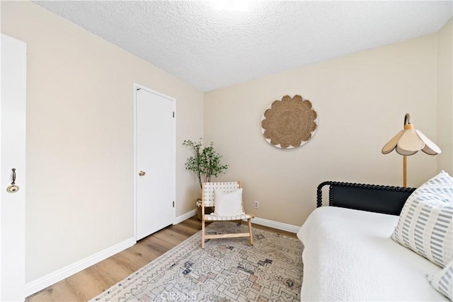 bedroom with light wood-style flooring, baseboards, and a textured ceiling