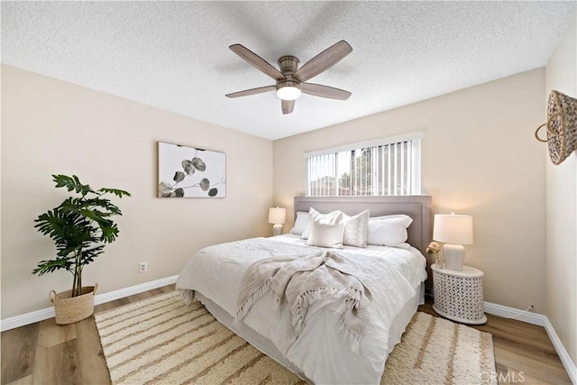 bedroom featuring a textured ceiling, ceiling fan, wood finished floors, and baseboards