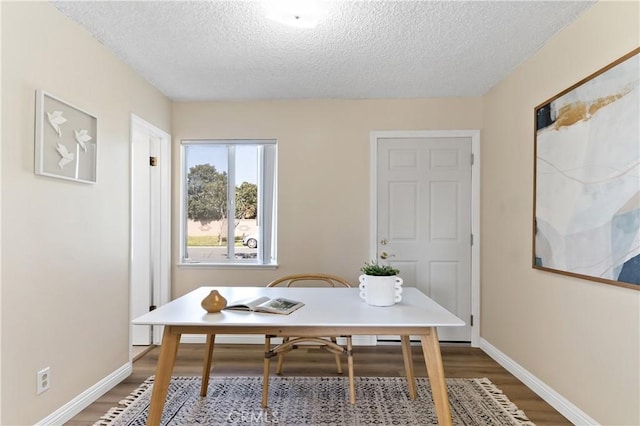 dining room featuring a textured ceiling, baseboards, and wood finished floors