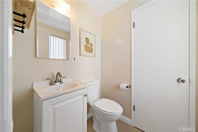 bathroom with baseboards, vanity, and toilet