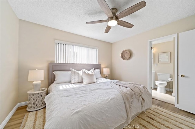 bedroom featuring a textured ceiling, ensuite bathroom, a ceiling fan, baseboards, and light wood-style floors