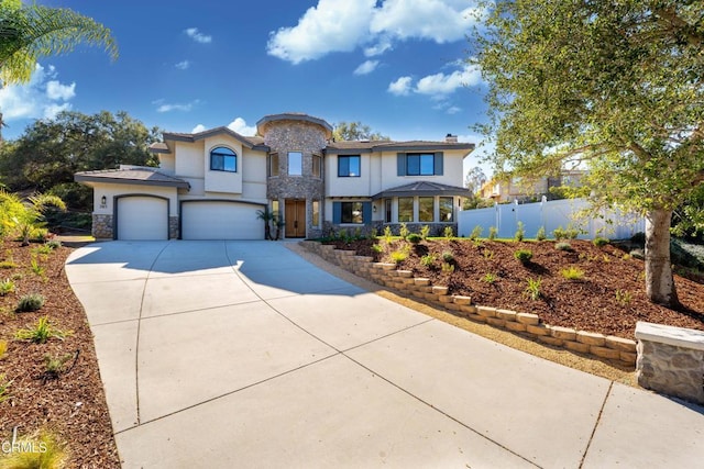 view of front of property with a garage, fence, stone siding, concrete driveway, and stucco siding