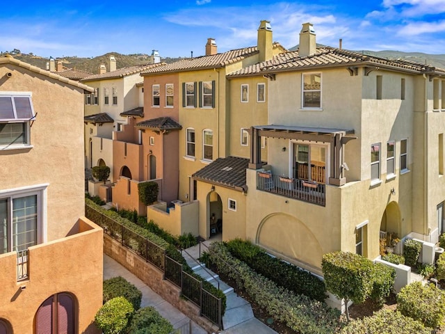 view of front of home with a pergola, a tile roof, a chimney, and stucco siding