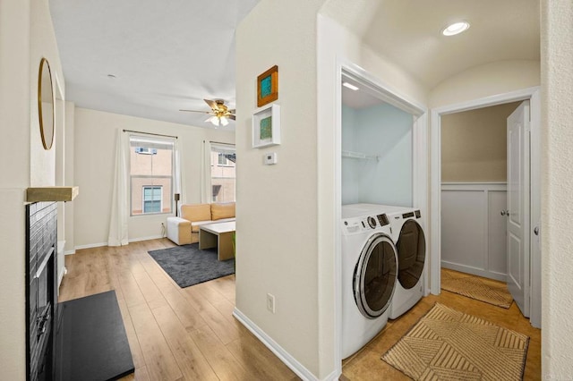 clothes washing area featuring ceiling fan, laundry area, separate washer and dryer, a fireplace, and light wood-type flooring