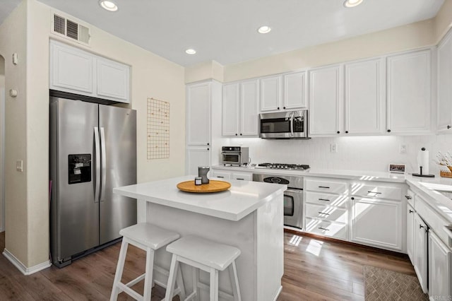 kitchen featuring visible vents, white cabinets, a kitchen island, appliances with stainless steel finishes, and dark wood-type flooring