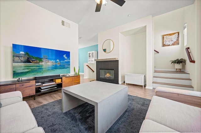 living area with stairway, visible vents, wood finished floors, and a glass covered fireplace