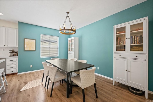 dining area with light wood-style floors, a chandelier, and baseboards