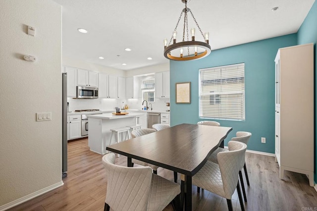 dining room with a chandelier, light wood-type flooring, baseboards, and recessed lighting