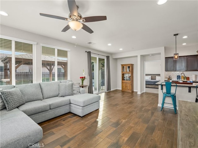 living room with ceiling fan, recessed lighting, dark wood-type flooring, visible vents, and baseboards