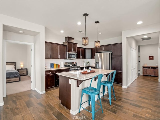 kitchen featuring visible vents, backsplash, appliances with stainless steel finishes, dark brown cabinetry, and light stone countertops