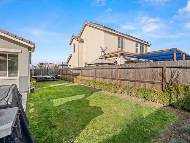 view of yard featuring a trampoline and a fenced backyard