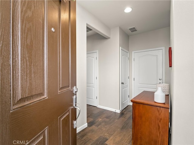 corridor featuring dark wood-style flooring, visible vents, and baseboards