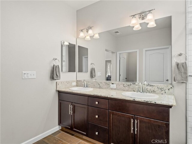 bathroom featuring double vanity, a sink, visible vents, and baseboards