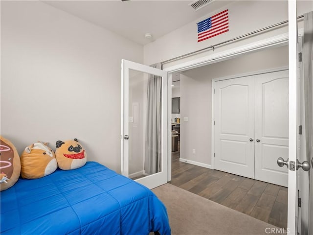 bedroom featuring baseboards, a closet, visible vents, and wood finished floors