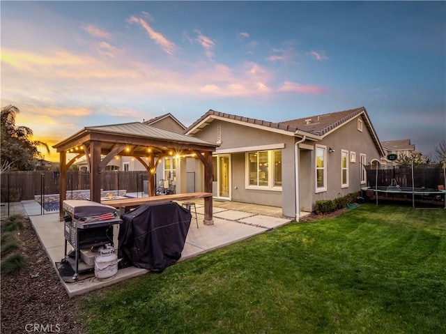 back of house with a patio, a fenced backyard, a trampoline, a gazebo, and stucco siding