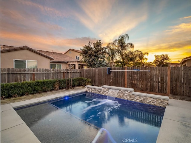 pool at dusk with a fenced backyard