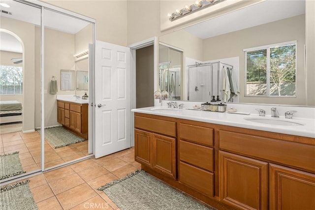 ensuite bathroom with double vanity, a sink, and a healthy amount of sunlight