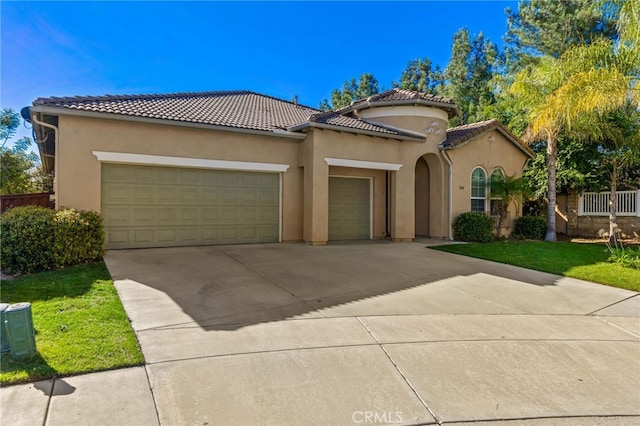 mediterranean / spanish home featuring a garage, concrete driveway, a tiled roof, and stucco siding