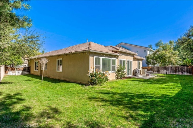 back of property with a patio area, a fenced backyard, a tile roof, and a yard