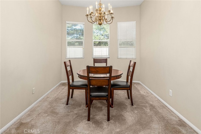 carpeted dining space with baseboards and a chandelier