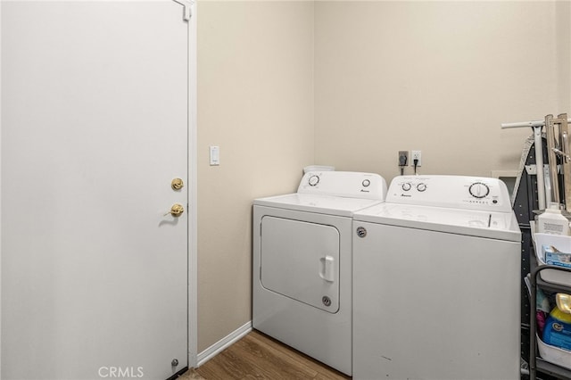 washroom with laundry area, baseboards, wood finished floors, and washing machine and clothes dryer