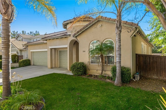 mediterranean / spanish-style house featuring a garage, a front yard, fence, and stucco siding