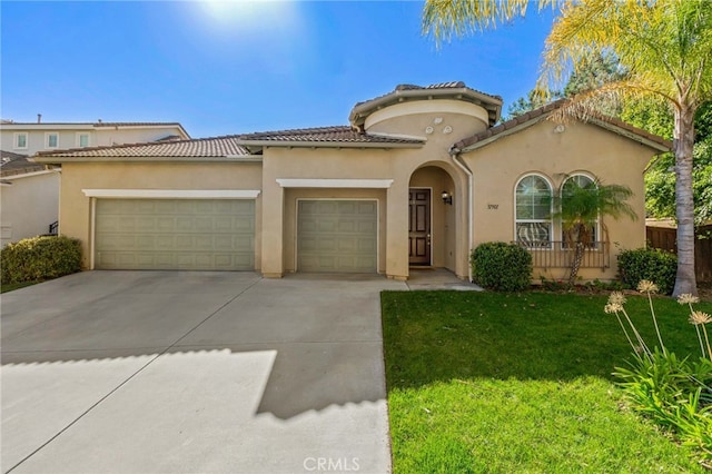 mediterranean / spanish-style home featuring a garage, driveway, a tile roof, a front lawn, and stucco siding