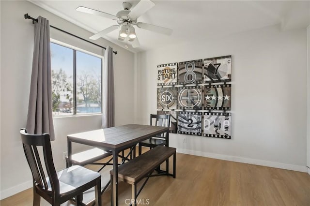 dining space with a ceiling fan, baseboards, and wood finished floors