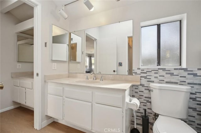 bathroom with toilet, wood finished floors, tile walls, and vanity