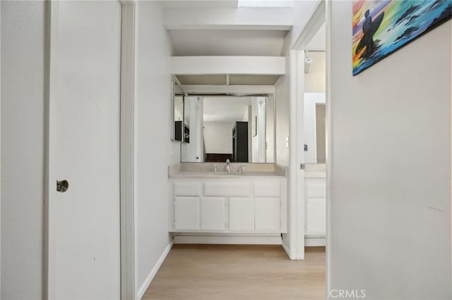 bathroom with wood finished floors, vanity, and baseboards