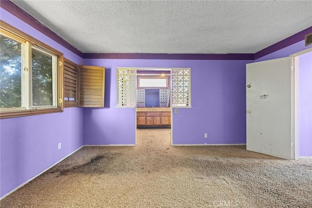 spare room featuring visible vents, carpet flooring, a textured ceiling, and baseboards