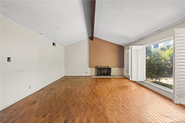 unfurnished living room featuring vaulted ceiling with beams, a textured ceiling, and wood finished floors