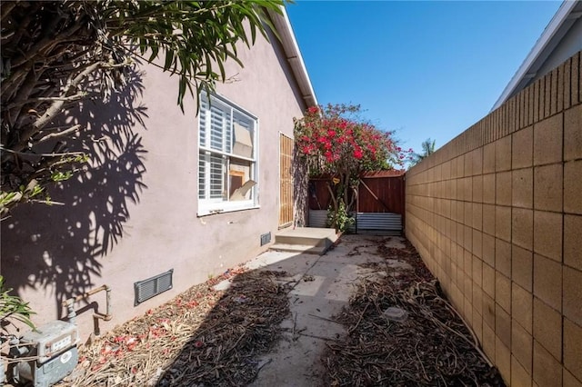 view of side of home with a patio area, a fenced backyard, and stucco siding