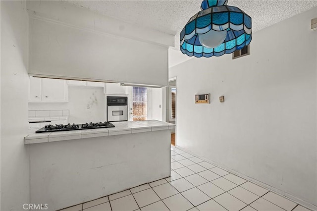 kitchen featuring visible vents, tile counters, oven, black gas cooktop, and white cabinetry