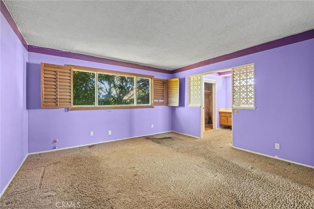 unfurnished room with a textured ceiling, baseboards, and carpet flooring