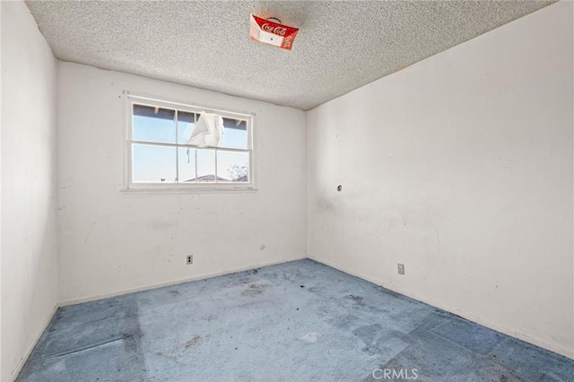 unfurnished room featuring carpet and a textured ceiling